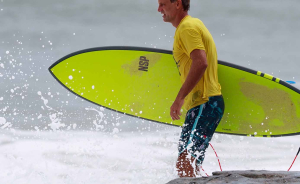 Man running into sea with a surf board